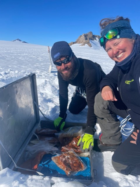Two researchers look in a box with food during fieldwork in Antarctica